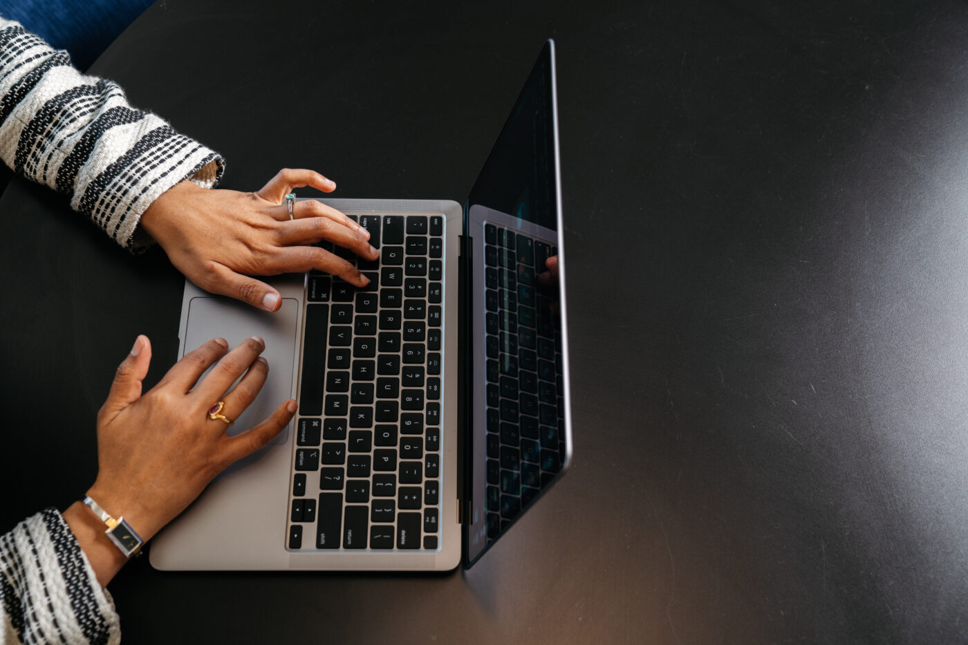 Image shows a persons hands typing using a laptop